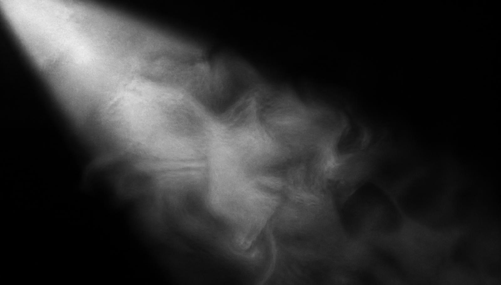 Smoke drifting through a single beam of light